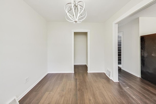 unfurnished dining area featuring an inviting chandelier and dark wood-type flooring