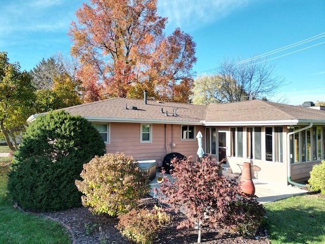 back of house featuring roof with shingles, a sunroom, and a patio area