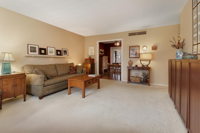 living area featuring baseboards, visible vents, and light carpet