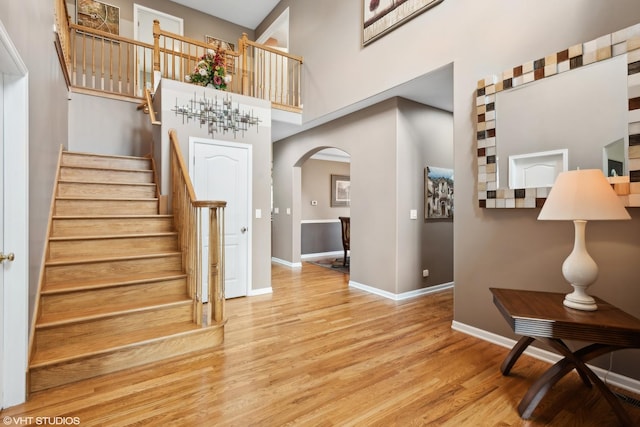 stairway with hardwood / wood-style flooring and a towering ceiling