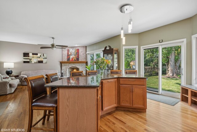 kitchen with decorative light fixtures, light hardwood / wood-style flooring, a kitchen breakfast bar, a kitchen island, and stainless steel appliances