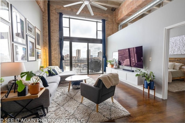 living area featuring ceiling fan, a towering ceiling, and wood finished floors