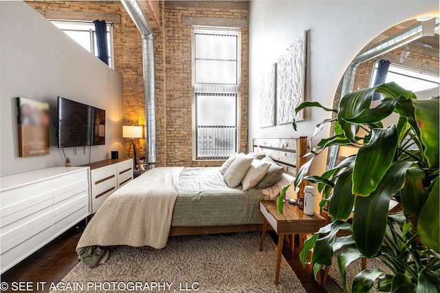 bedroom with a towering ceiling and brick wall