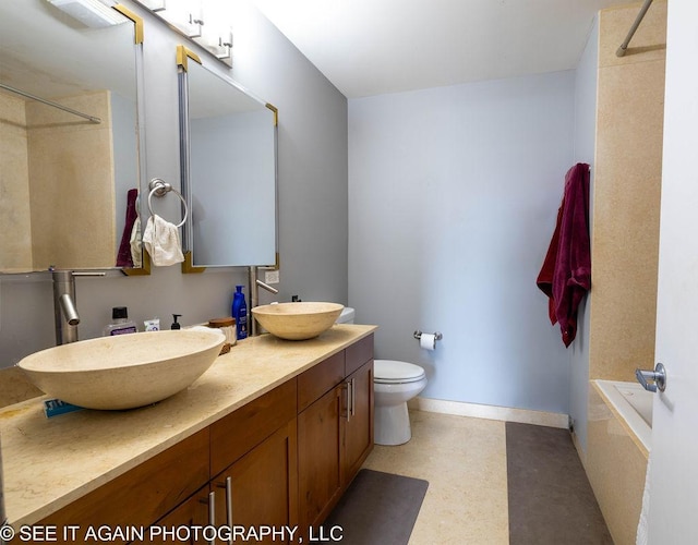 bathroom featuring a tub to relax in, a sink, baseboards, and double vanity