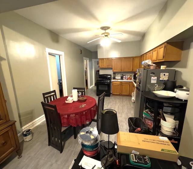 kitchen with gas stove, stainless steel fridge, ceiling fan, and light hardwood / wood-style flooring