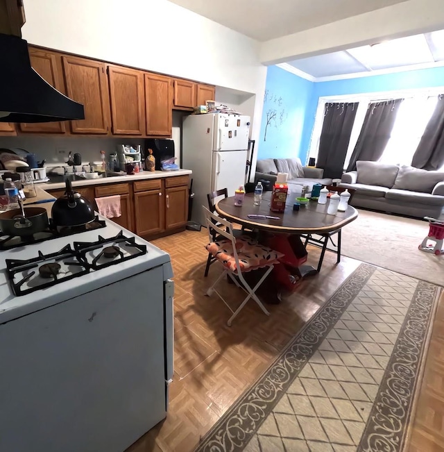 kitchen featuring white appliances, sink, exhaust hood, and light parquet floors