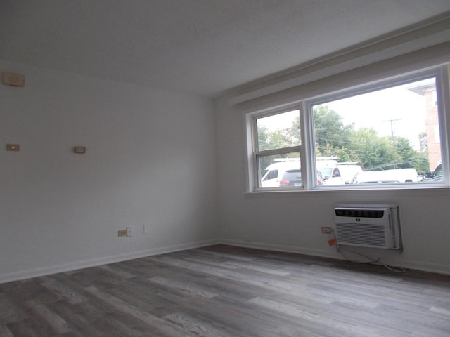 spare room featuring hardwood / wood-style floors, an AC wall unit, and a healthy amount of sunlight