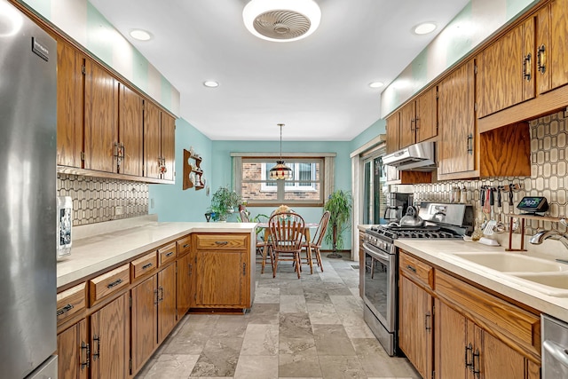 kitchen featuring decorative light fixtures, sink, decorative backsplash, kitchen peninsula, and stainless steel appliances