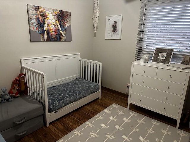 bedroom featuring dark hardwood / wood-style floors and a crib