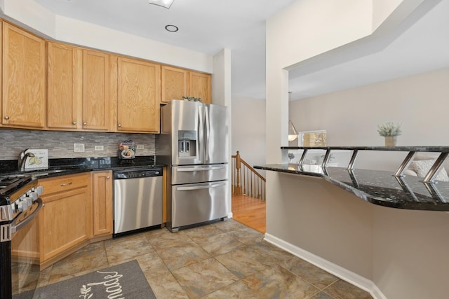 kitchen with appliances with stainless steel finishes, dark stone countertops, a sink, and decorative backsplash