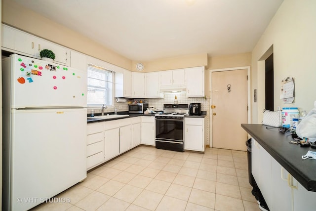 kitchen with stainless steel microwave, dark countertops, gas range oven, and freestanding refrigerator