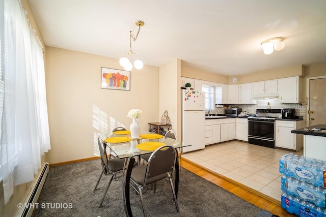 kitchen featuring a baseboard heating unit, stainless steel microwave, dark countertops, freestanding refrigerator, and gas stove