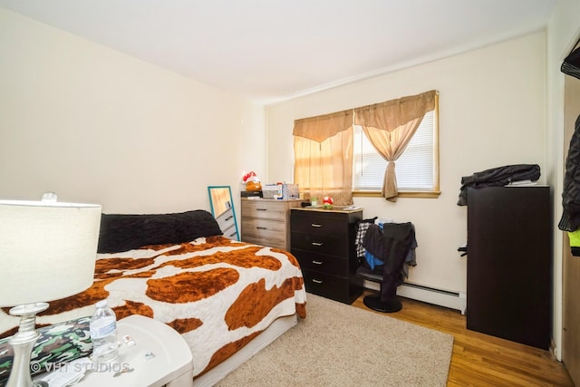 bedroom with a baseboard radiator and wood finished floors