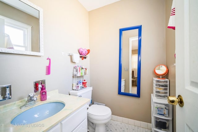 half bathroom with tile patterned flooring, toilet, vanity, and baseboards