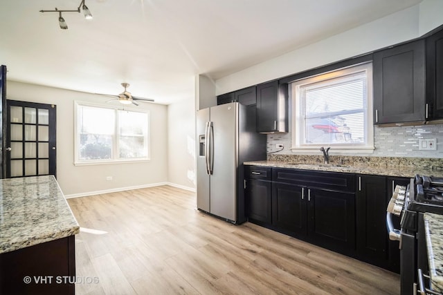 kitchen featuring a sink, range with gas stovetop, stainless steel fridge, and tasteful backsplash