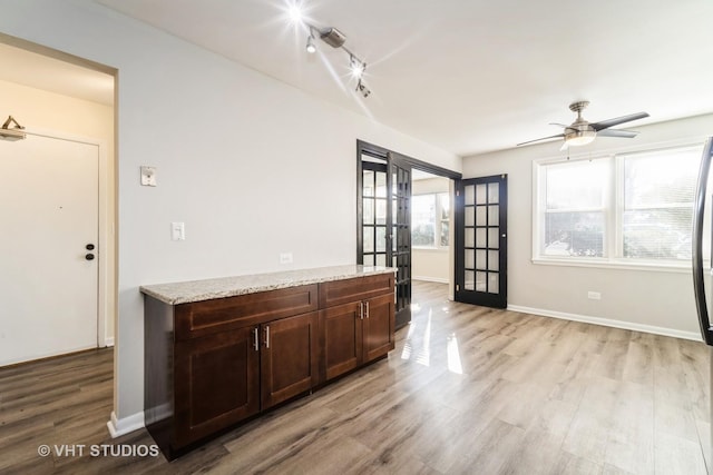 interior space featuring a ceiling fan, light wood-style floors, baseboards, and french doors