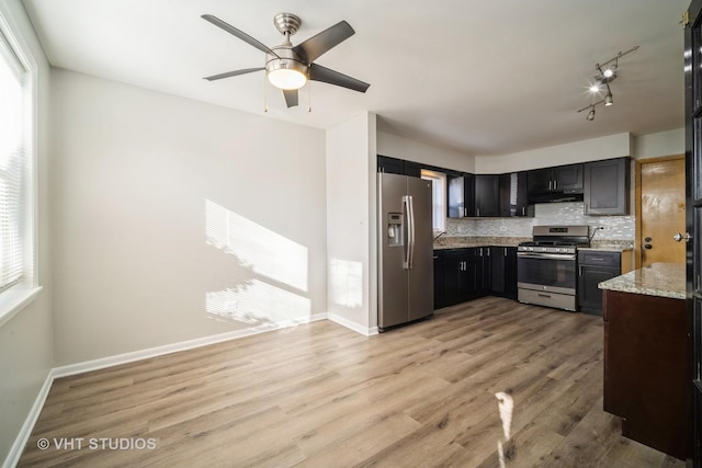 kitchen featuring light stone countertops, baseboards, light wood-style flooring, appliances with stainless steel finishes, and tasteful backsplash