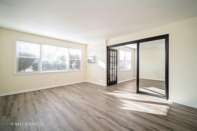 unfurnished room featuring baseboards, wood finished floors, and a wall unit AC