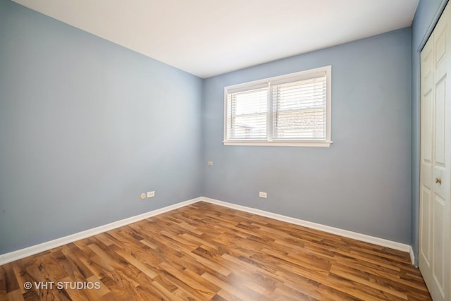 unfurnished bedroom with a closet, baseboards, and wood finished floors