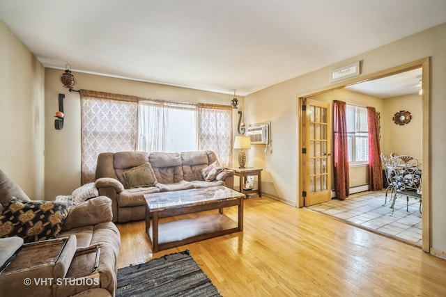 living area with a wall mounted air conditioner, plenty of natural light, wood finished floors, and baseboard heating