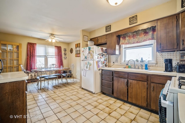 kitchen featuring a sink, white appliances, a wealth of natural light, and light countertops