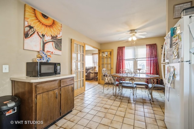 kitchen with light tile patterned flooring, a healthy amount of sunlight, light countertops, and black microwave