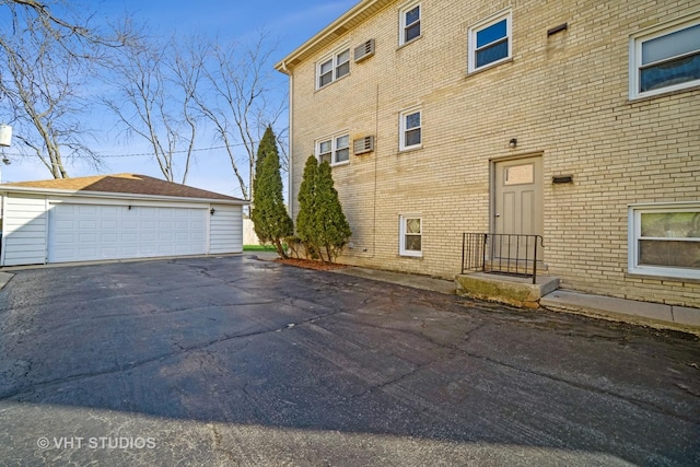 view of side of property with brick siding, a detached garage, and an outdoor structure