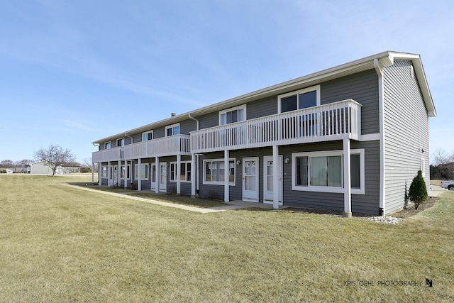 rear view of house with a yard and a balcony