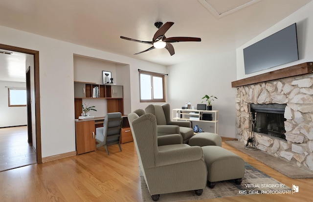 living area featuring light wood-style flooring, a fireplace, and ceiling fan