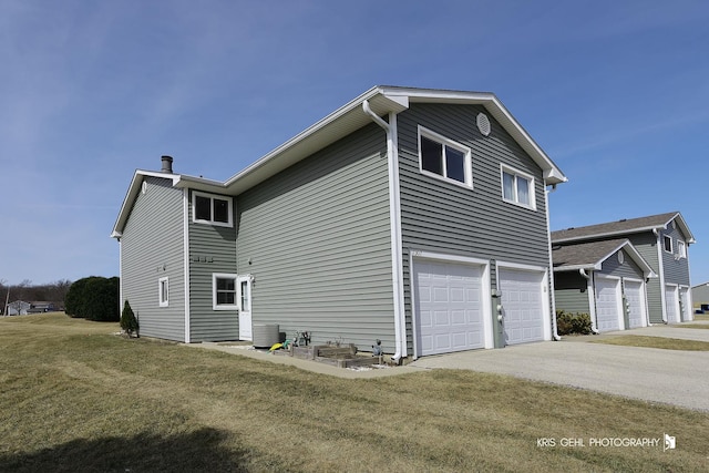 view of side of property featuring a lawn, a garage, and driveway