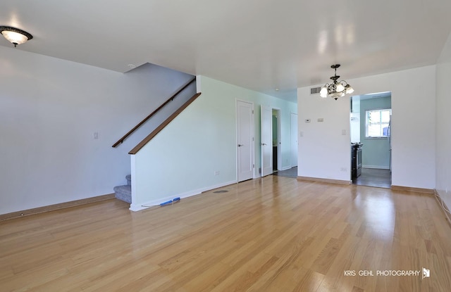 unfurnished living room with stairway, visible vents, baseboards, light wood-style flooring, and a notable chandelier