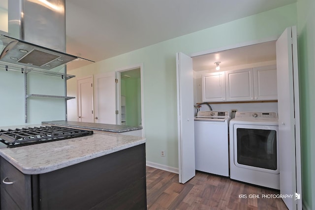 kitchen with baseboards, island exhaust hood, dark wood-type flooring, white cabinetry, and washer and clothes dryer