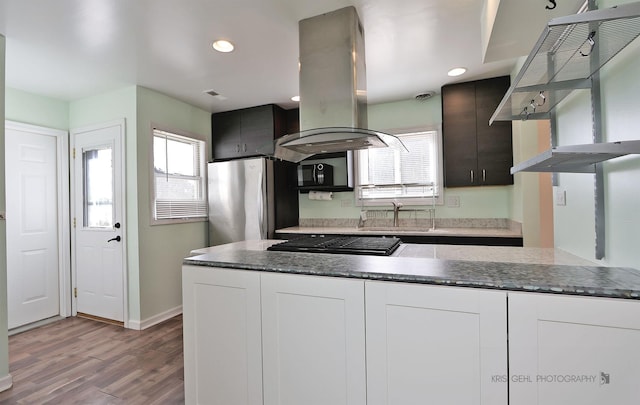 kitchen featuring gas cooktop, freestanding refrigerator, a sink, wall chimney range hood, and island range hood