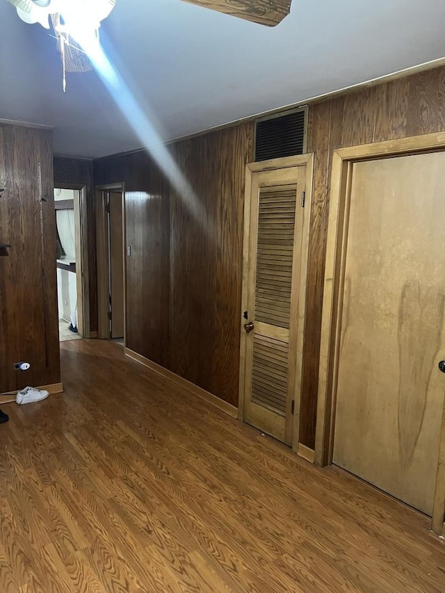 hall with wood-type flooring and wooden walls