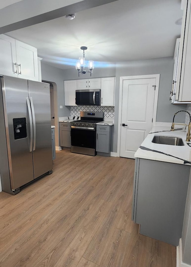 kitchen featuring stainless steel appliances, pendant lighting, gray cabinets, sink, and white cabinetry