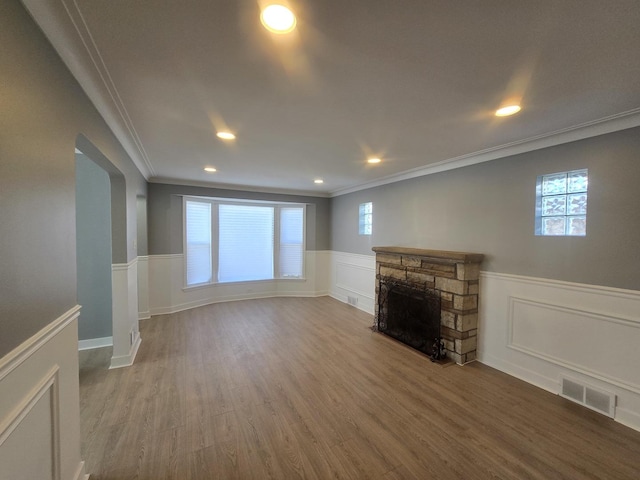 unfurnished living room with a fireplace, crown molding, and wood-type flooring