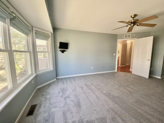 carpeted empty room featuring visible vents, ceiling fan, and baseboards