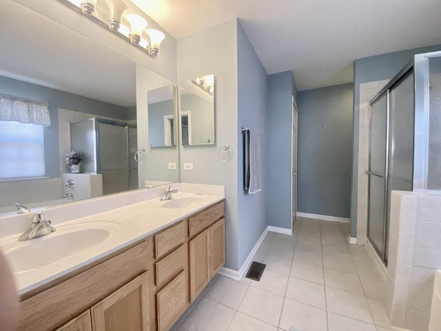 bathroom featuring tile patterned floors, double vanity, a stall shower, and a sink