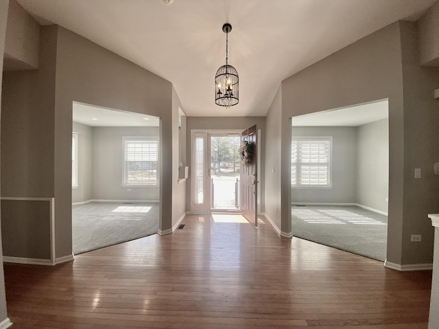 foyer entrance featuring wood-type flooring, plenty of natural light, lofted ceiling, and a chandelier