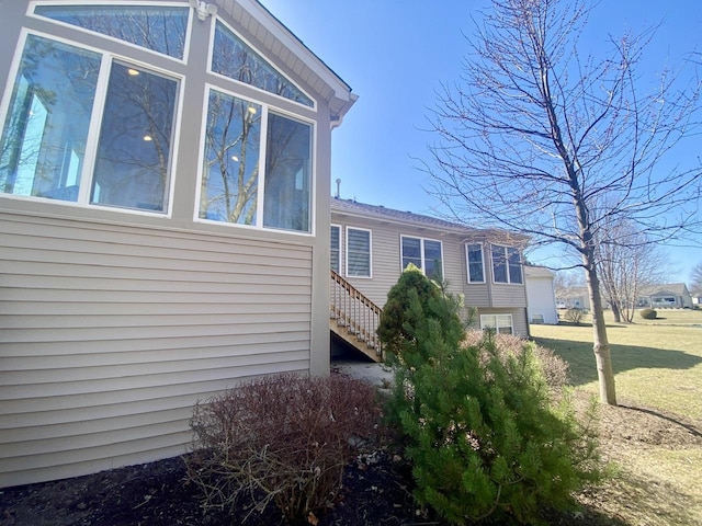 view of side of home featuring a yard, stairs, and a sunroom