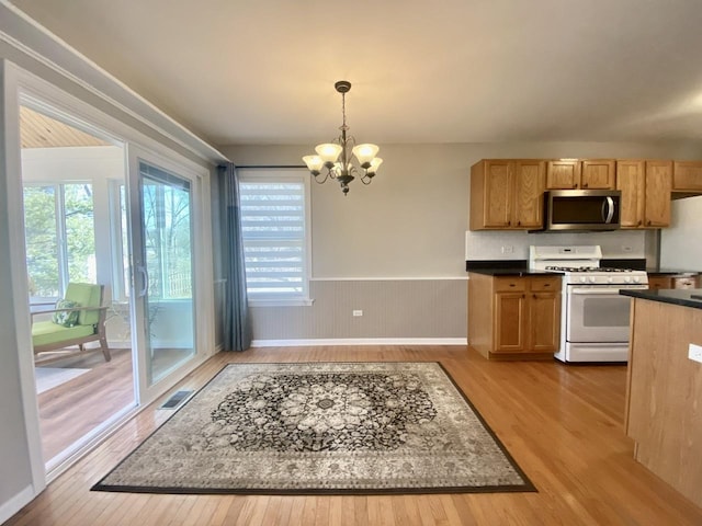 kitchen with visible vents, white range with gas cooktop, light wood-style flooring, stainless steel microwave, and a chandelier