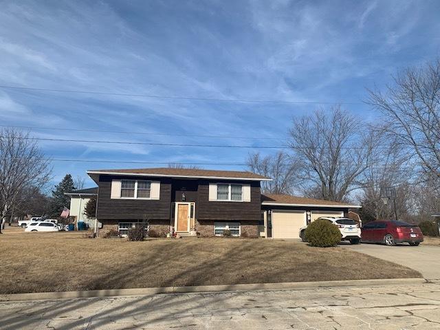 raised ranch featuring a garage and a front lawn