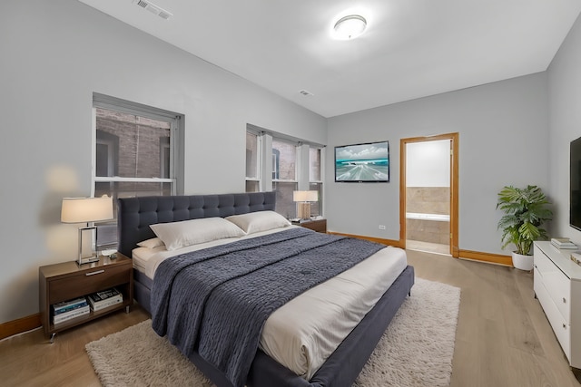 bedroom featuring hardwood / wood-style flooring and ensuite bathroom