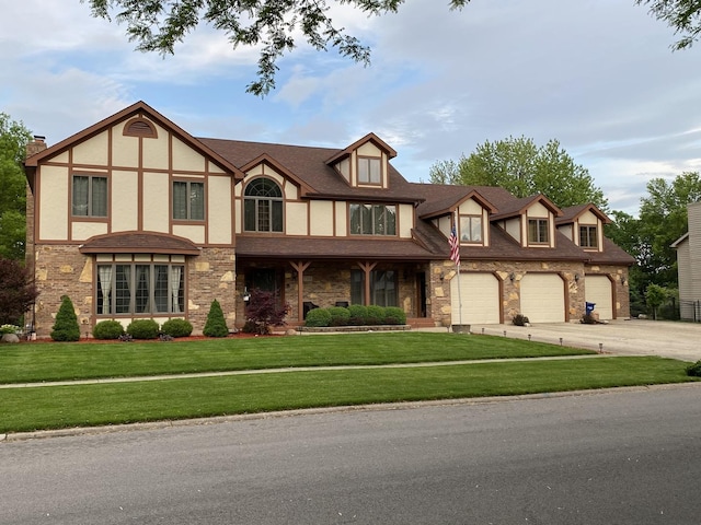 english style home featuring driveway, a front lawn, brick siding, and stucco siding