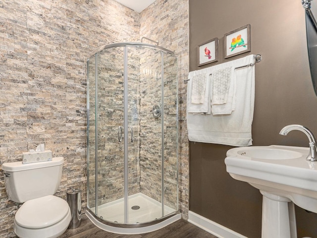 full bath with baseboards, a shower stall, toilet, and wood finished floors