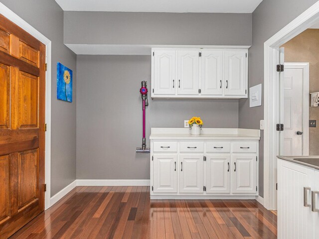 kitchen featuring dark wood-type flooring, light countertops, white cabinetry, and baseboards