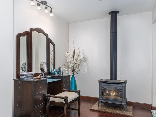 office space with dark wood-style floors, a wood stove, and baseboards