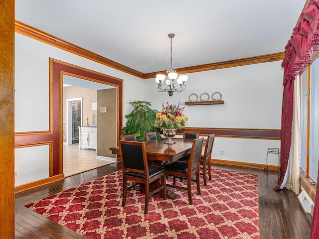 dining space featuring a chandelier, visible vents, crown molding, and hardwood / wood-style flooring