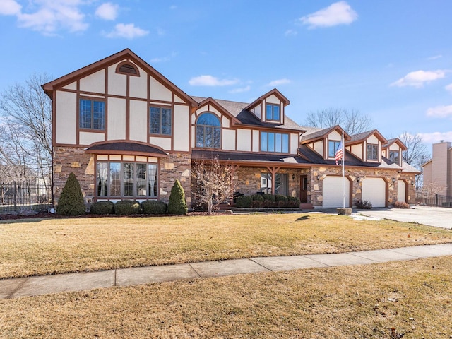 tudor home with a garage, driveway, fence, and a front lawn