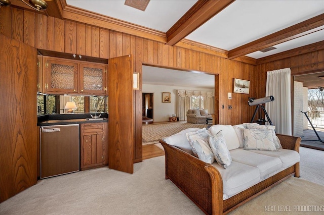 living area featuring light carpet, wooden walls, beamed ceiling, and a healthy amount of sunlight